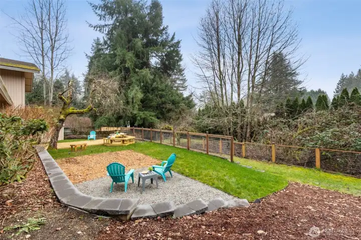 The wide back yard nestled up against a community green space, enjoys privacy year round.  Wide terraces offer an upper level with a wood chip yard structure base, gravel area for an outdoor fireplace, and lower ball toss area.