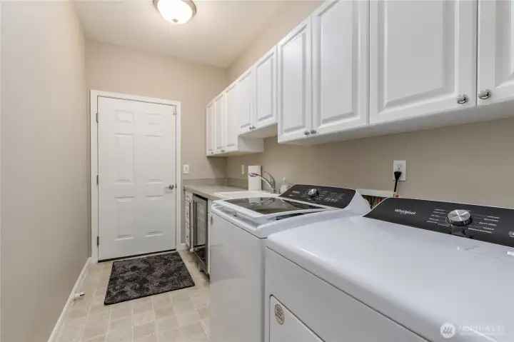 Laundry/mudroom includes utility sink, built-in cabinetry, and a beverage fridge. All appliances stay!