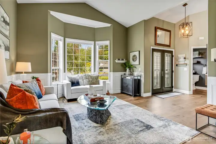A grand foyer flows seamlessly into the formal living room where vaulted ceilings, oversized wood-wrapped windows, and rich architecture details fill the space with warmth and light. A grand foyer flows seamlessly into the formal living room where vaulted ceilings, oversized wood-wrapped windows, and rich architecture details fill the space with warmth and light.