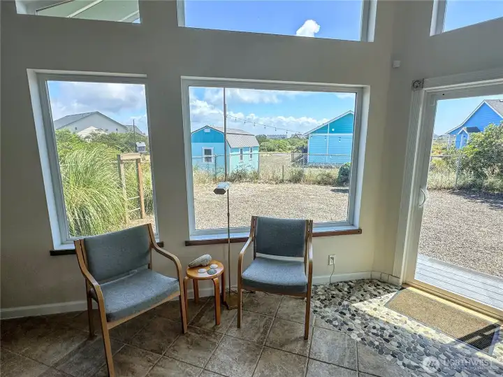 A charming sitting area to enjoy a peaceful morning coffee, or an evening read? You name it! Notice the beautiful stone flooring at the back door.