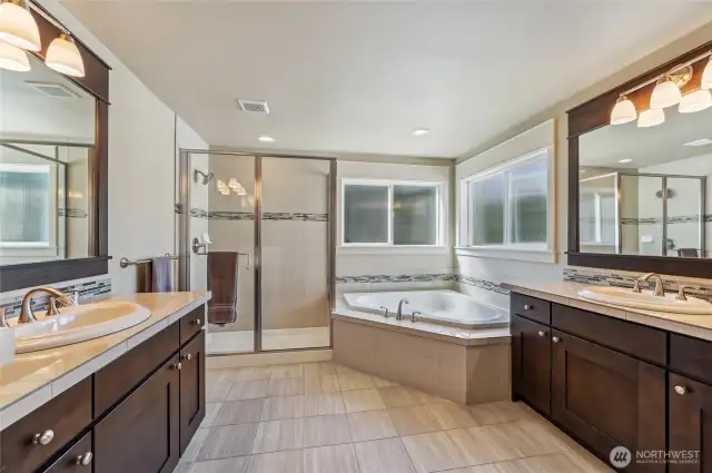 The primary bathroom is the perfect place to get ready for the day or to soak away the stress of a long day. Double vanities, step-in shower and large soaking tub are accented by beautiful tile works and rich wood cabinetry.