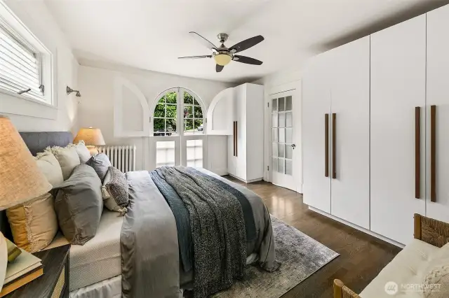 Main floor primary bedroom with attached bath. Arched windows are doors which fully open.