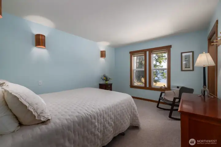 Primary bedroom on main floor has bay views out the large windows and lovely copper sconces.