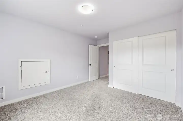 The south bedroom with views of the greenbelt, skies, and south flank of the Olympic Mountain Range including Mt. Ellinor. The wall door provides attic and furnace access with decking and lighting.