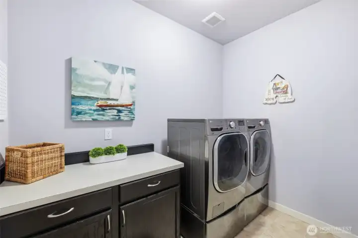LG ThinQ washer and gas dryer in spacious laundry with folding table.