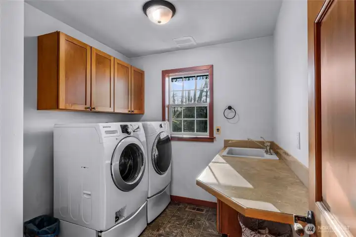 Laundry room includes utility sink, storage,  and exterior access. Designed for efficiency  and everyday use.