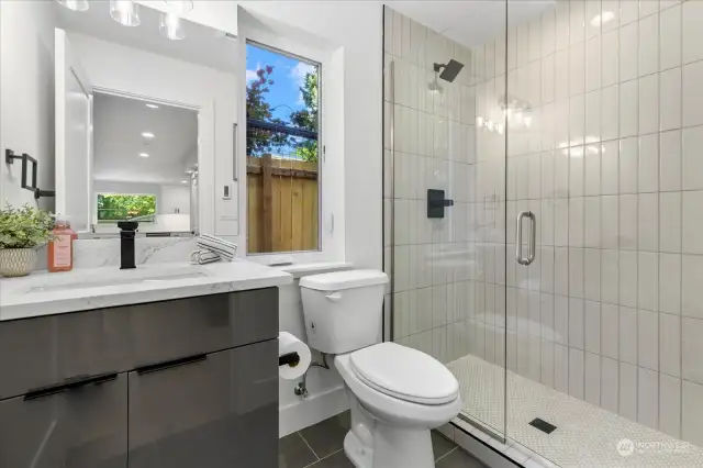 Downstairs 3/4 bath with heated floor, custom tiled shower, and quartz-topped vanity.