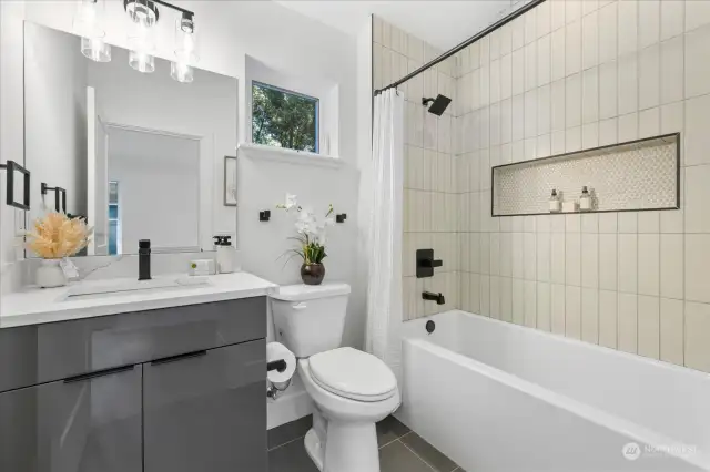 Upstairs full bathroom with heated floors, custom tiled-tub, and quartz-topped vanity.  Vaulted ceilings make this space bright and airy.