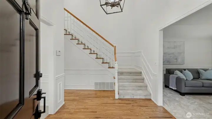 Vaulted ceiling with wainscot details and beautiful refinished hardwood floors lend elegance to the entry and main level rooms.