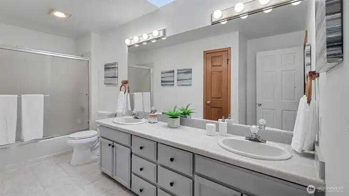 Upstairs hall bathroom with dual vanities and skylight.