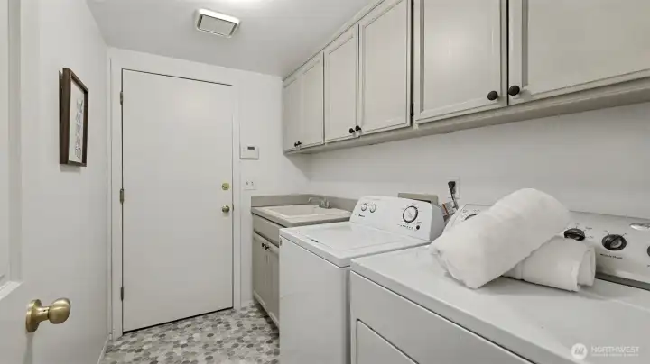 Utility room features freshly painted cabinetry, generous utility sink and new vinyl flooring.