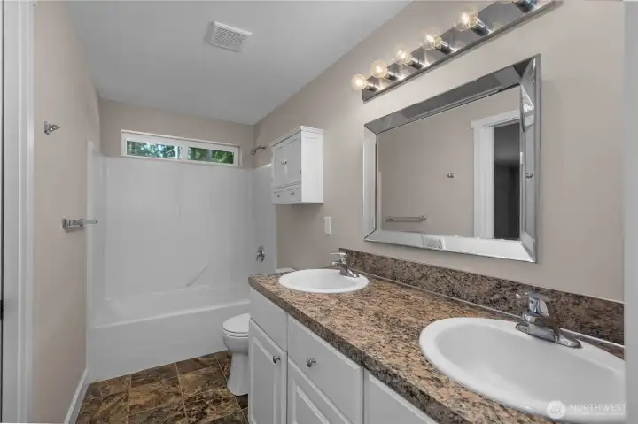 Primary bath with dual-sink vanity, tub/shower combo, tile flooring, and updated toilet. Primary bath with dual-sink vanity, tub/shower combo, tile flooring, and updated toilet.