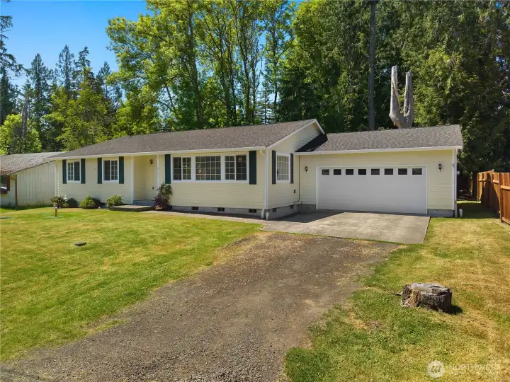 Classic rambler exterior with attached 2-car garage, driveway parking, and mature trees nearby. Classic rambler exterior with attached 2-car garage, driveway parking, and mature trees nearby.