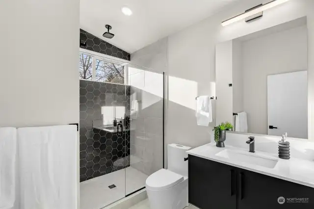 This stunning bath features a full tub, clerestory windows, custom tiling & quartz counters!