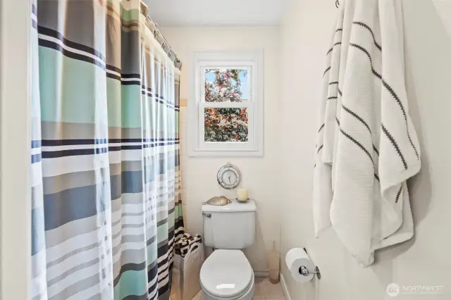 The shower and toilet are separated by pocket doors from the guest bath vanity.