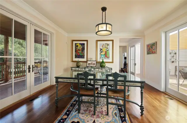 Dining room with French doors that open to expansive decks on both sides.