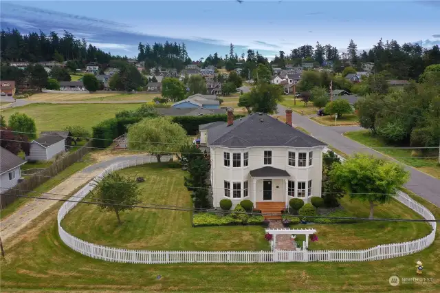 The Tuscan-inspired landscaping, complete with a picket fence, raised garden beds, and expansive decks, enhances the home's Italianate charm.