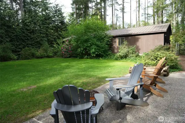 Backyard has a large concrete patio.  The building to the side is the detached 6 car garage.