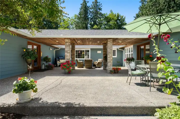 Charming entrance with mature greenery and rustic wood beams.