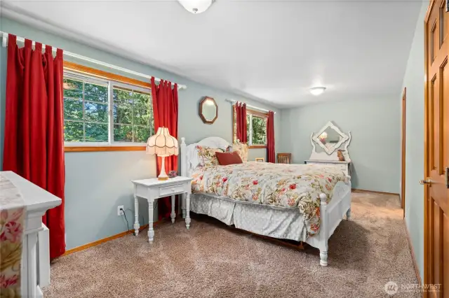 Tranquil bedroom with plush carpet and lush outdoor views.