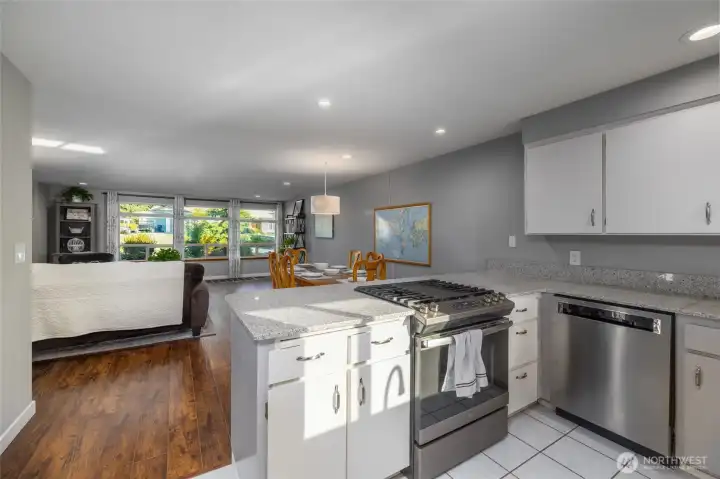 Kitchen has tile floor, quartz counters, and is open to the living and dining areas.