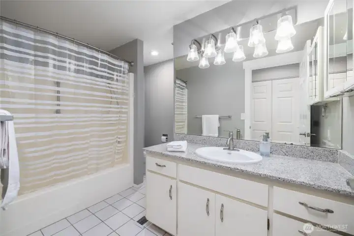 Full guest bath with granite counter, tile floor, tub/shower.
