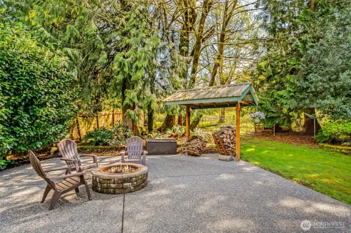 Fire pit patio with covered wood storage. The gate to the orchard is just beyond.