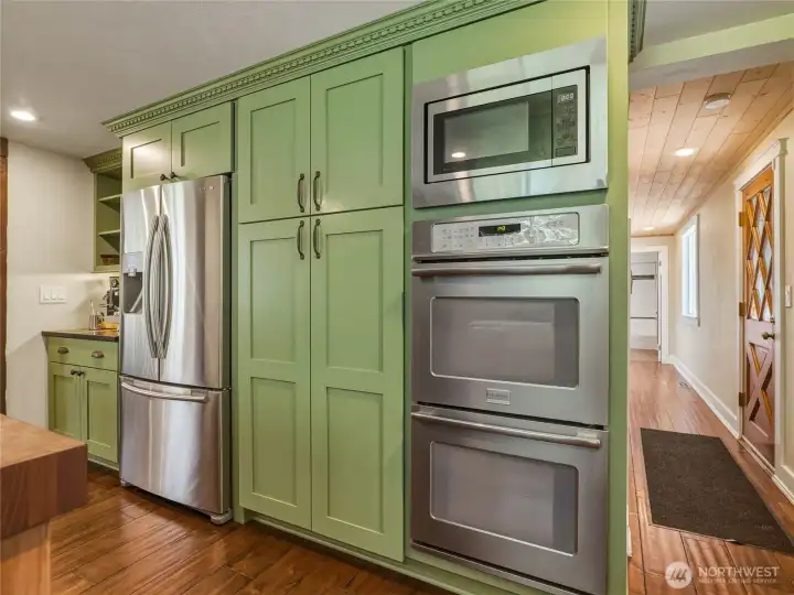 Beautiful custom pantry with slide-out shelving, built-in double oven and microwave, stainless refrigerator and coffee bar