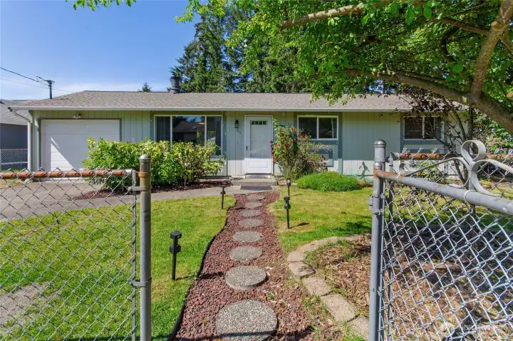 Gorgeous entry view through fully fenced yard with walk way to front door