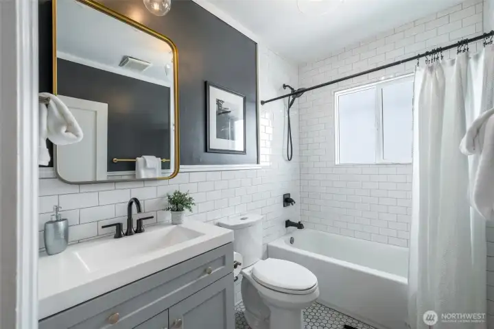 The full size bath on the main floor, fully remodeled in 2018 with hex tile floors, subway tile surround up to the ceiling and a porcelain sink and vanity.