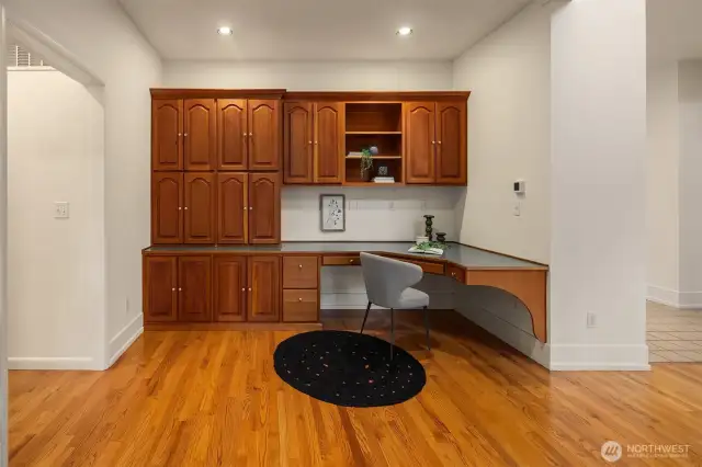 Just off the living room, this custom built-in workspace offers an ideal setup for remote work, creative projects, or household organization. With abundant upper and lower cabinetry, there's no shortage of storage for office supplies, files, or personal items. The wraparound desk provides generous surface area for multiple monitors or tasks, and integrated lighting keeps the space functional and bright. Whether used as a home office, study nook, or planning center, this area blends seamlessly into the home while adding practical value.