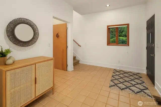 The spacious entryway offers a practical and welcoming hub at the heart of the home, with access points leading both upstairs and down. The tile flooring is durable and easy to maintain—perfect for the Pacific Northwest seasons. A window adds natural light and a touch of warmth, while the staircases provide a functional flow to the multi-level layout. Whether you're greeting guests, heading to the lower level, or starting your day upstairs, this entry sets the tone with clean lines, simplicity, and room to move.