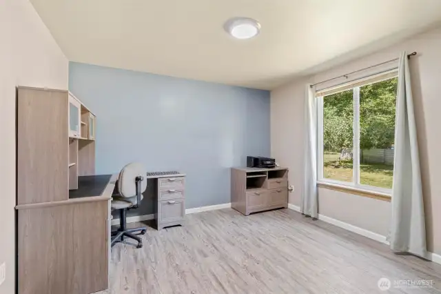 This spacious secondary bedroom is filled with natural light thanks to the large window overlooking the private front yard. A calming accent wall adds a modern touch, while the versatile layout easily accommodates a guest bed, creative space, or a full home office setup. Durable flooring and neutral finishes make this room move-in ready for whatever your lifestyle needs.