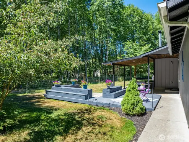 Enjoy your own private outdoor retreat with this beautifully designed covered patio and custom-built deck surrounded by nature. Perfect for entertaining, dining al fresco, or simply relaxing under the trees, this inviting space overlooks a fully fenced yard and backs to lush forest for added privacy. Whether you're enjoying morning coffee, hosting summer BBQs, or winding down in the evening, this peaceful backyard offers a tranquil lifestyle on nearly 8 acres in rural Lewis County. Outdoor living at its finest with plenty of room to garden, roam, or just breathe in the quiet.