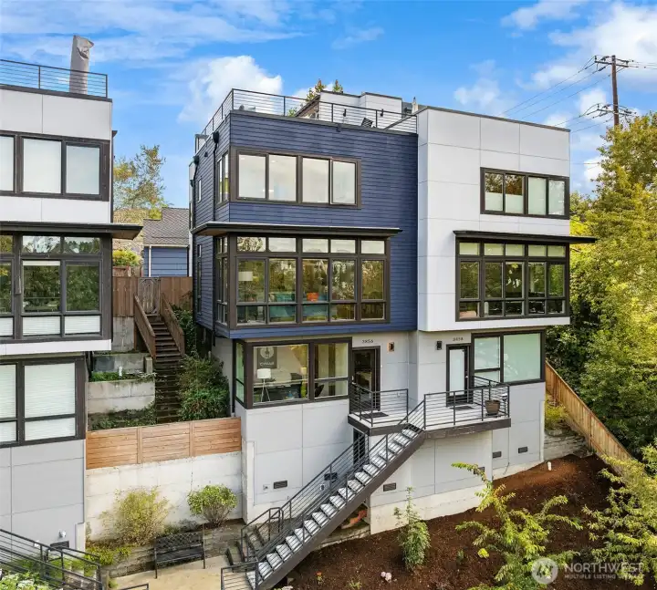 Blue home, one shared wall with white neighbor home. Perched high above the trees.