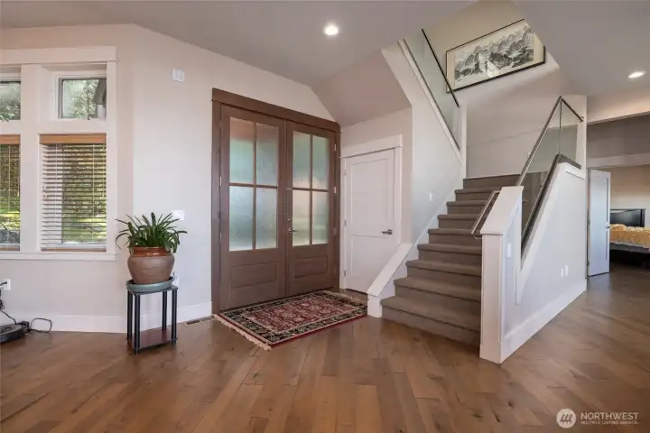 View of entry from the interior. Hardwood floors throughout downstairs living areas. Stair at right brings you up to the oversize bonus room. 10'-0" ceilings on the main level allow for expansive views and light from the oversize windows.
