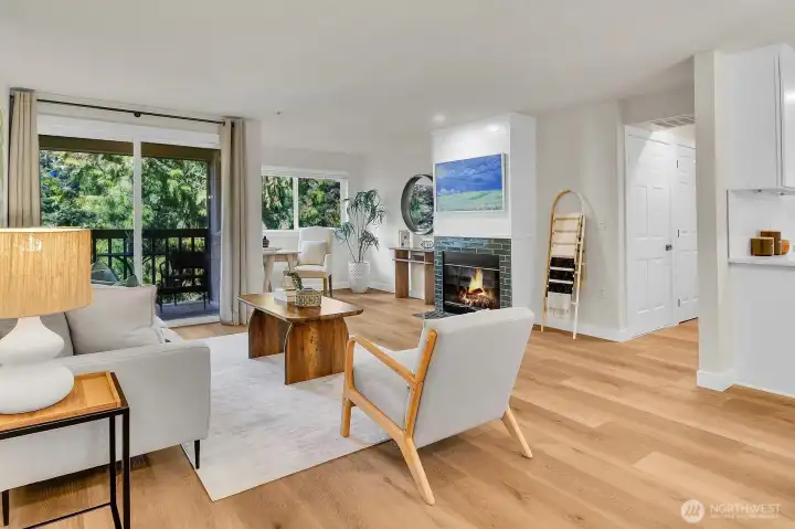 Light-filled living room with inviting fireplace focal point and seamless access to a private balcony surrounded by lush greenery.