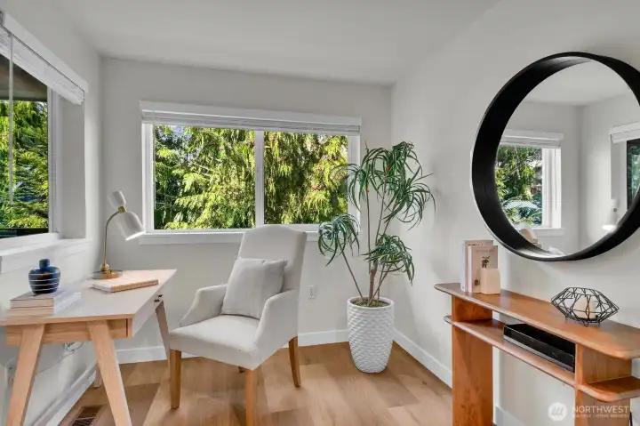 Bright office nook with large windows—perfect for work-from-home with peaceful, tree-lined views.