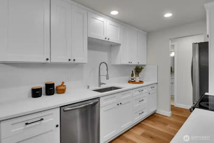Bright galley-style kitchen featuring stainless steel appliances and abundant cabinet storage.