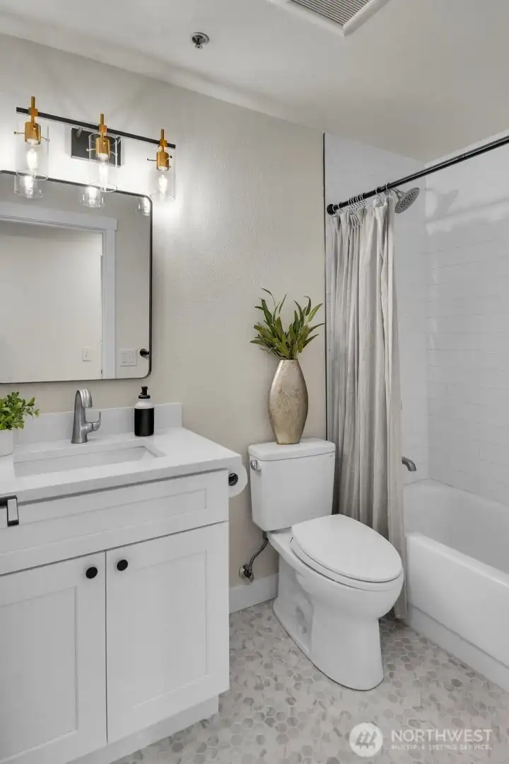 Remodeled bathroom featuring a quartz vanity, updated fixtures, and subway tile shower surround.