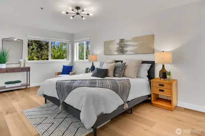 Generous primary suite filled with natural light, featuring ample space and serene tree-lined views.