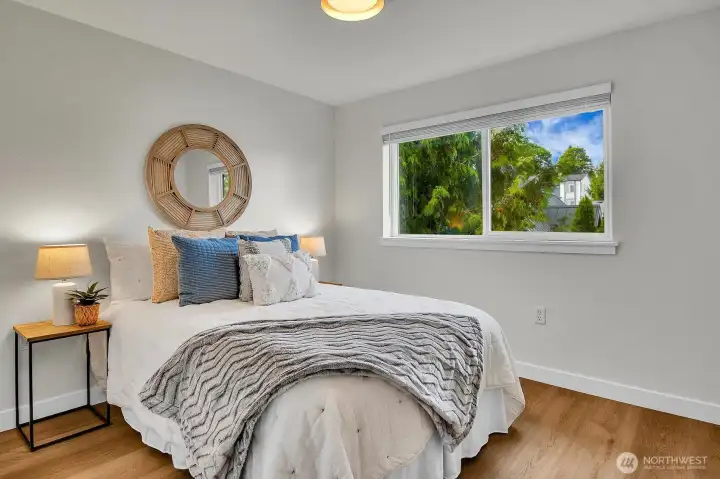 Bright secondary bedroom with large window, peaceful outlook, and fresh, modern finishes.