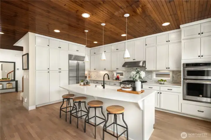 Spacious quartz island and sub zero refrigerator with gas cooktop, full height white cabinets with under cabinet lighting. Spacious quartz island and sub zero refrigerator with gas cooktop, full height white cabinets with under cabinet lighting.