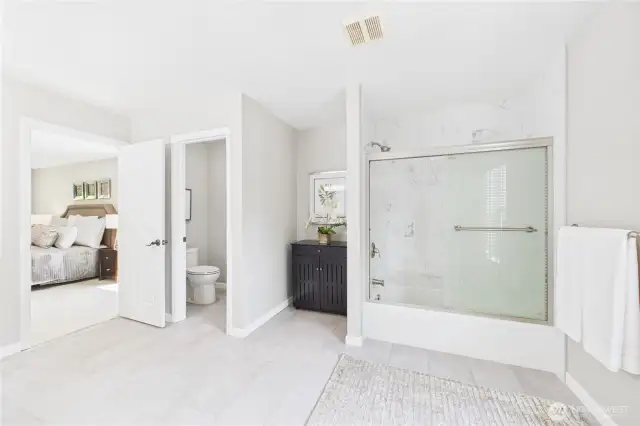 Unwind in the remodeled primary bath, featuring a large vanity, modern tile flooring, and a sleek tub/shower combo with marble tile accents. A calming space with elegant design and generous proportions.