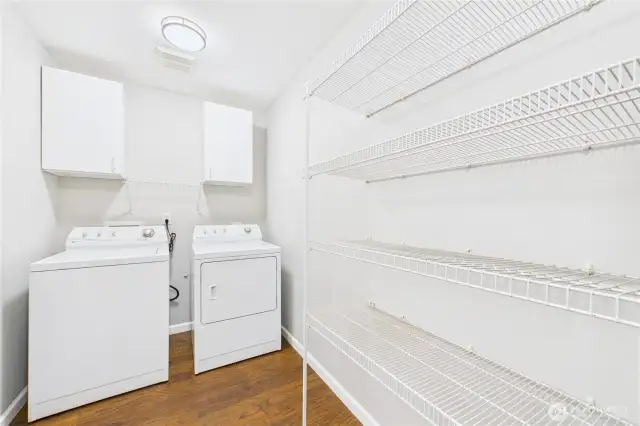This well-designed laundry room is both practical and spacious, complete with washer, dryer, upper cabinetry, and extensive wire shelving for all your storage and organization needs.