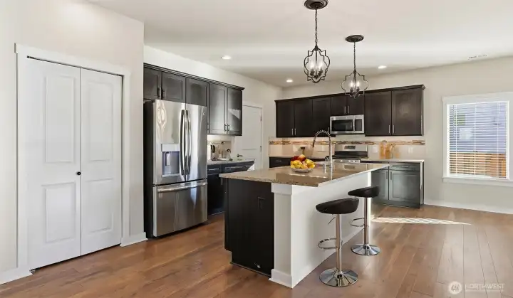 Gourmet kitchen offers a large center island, granite countertops with full-height backsplash, stainless-steel appliances and convenient pantry.