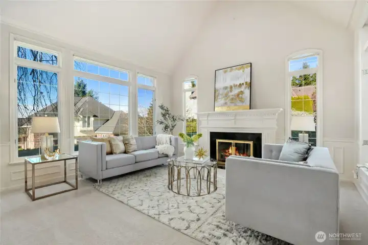 Sun-drenched living room with soaring ceilings, expansive windows, and a cozy fireplace An elegant space designed for both relaxed living and entertaining.