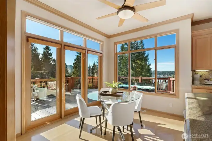 Casual dining with panoramic windows and direct deck access, offering serene treetop and lake views for effortless indoor-outdoor living.