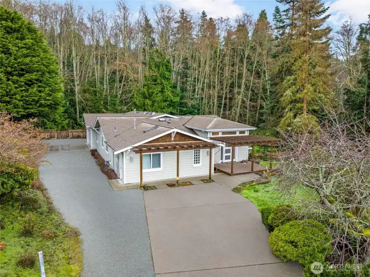 Bird’s-eye view reveals the home's cul-de-sac location, ample driveway parking, and private wooded backdrop.
