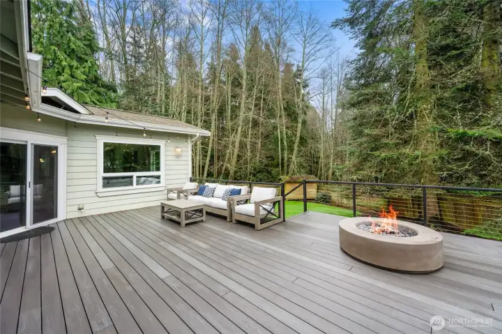 Expansive low-maintenance composite deck creates the perfect outdoor living space, complete with modern fire feature and peaceful views of the surrounding trees.